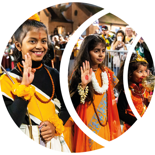 Three girls stand in front of a crowd while taking part in Woking’s Diwali celebrations