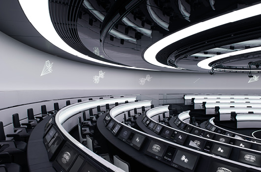 A futuristic, circular conference room with screens in front of each chair